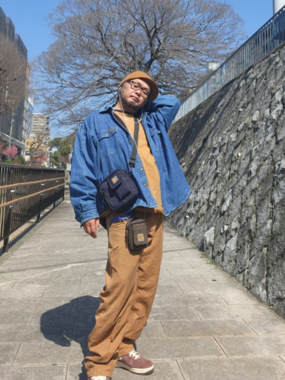 ブラウン系のスニーカー、ブラウン系のカーゴパンツ、ブルー系のショルダーバッグを着用したメンズの春コーディネートの2枚目の写真
