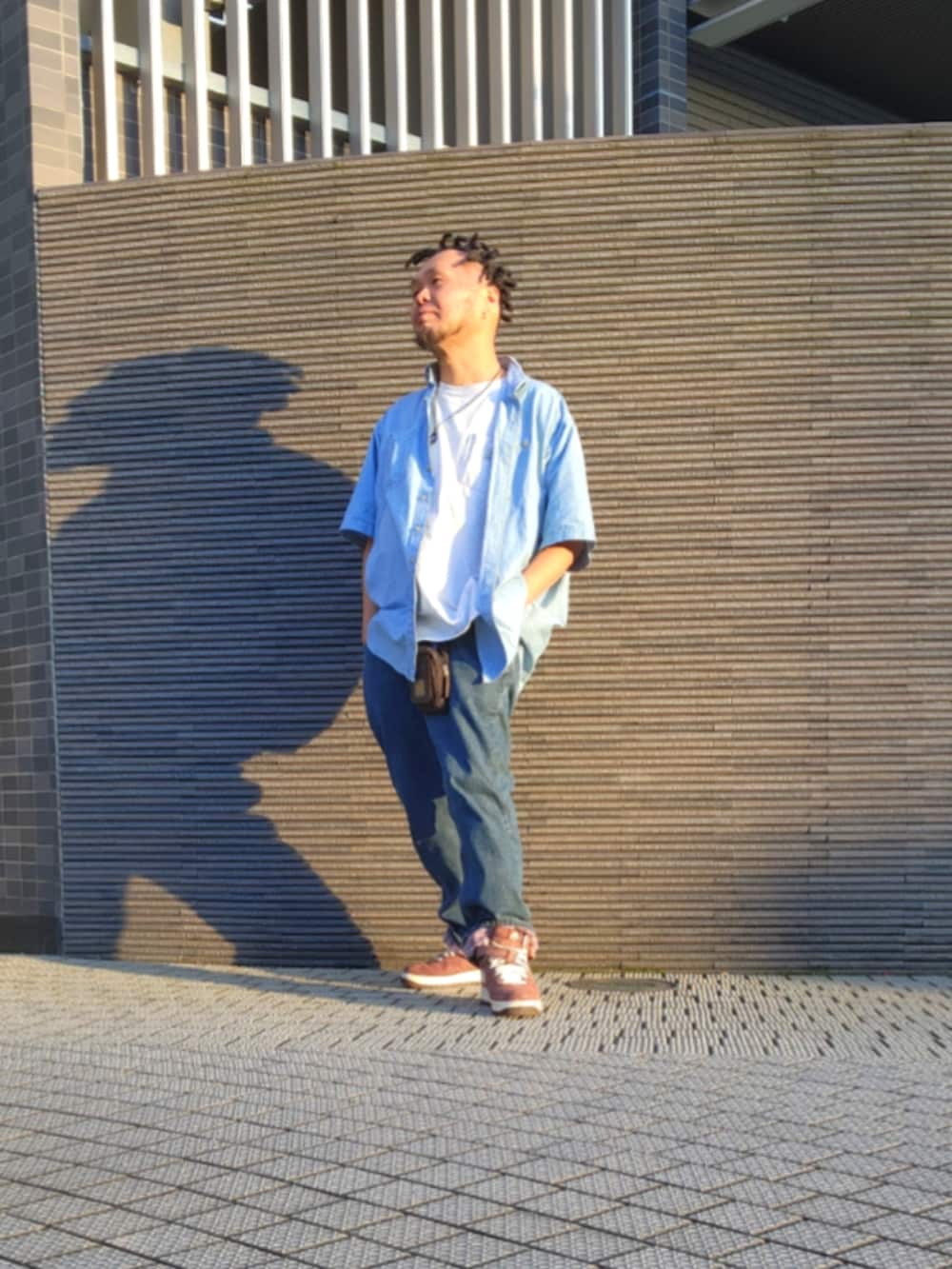 ブラウン系のスニーカー、ブルー系のデニムパンツ、ホワイト系のTシャツ/カットソーを着用したメンズの春コーディネートの3枚目の写真