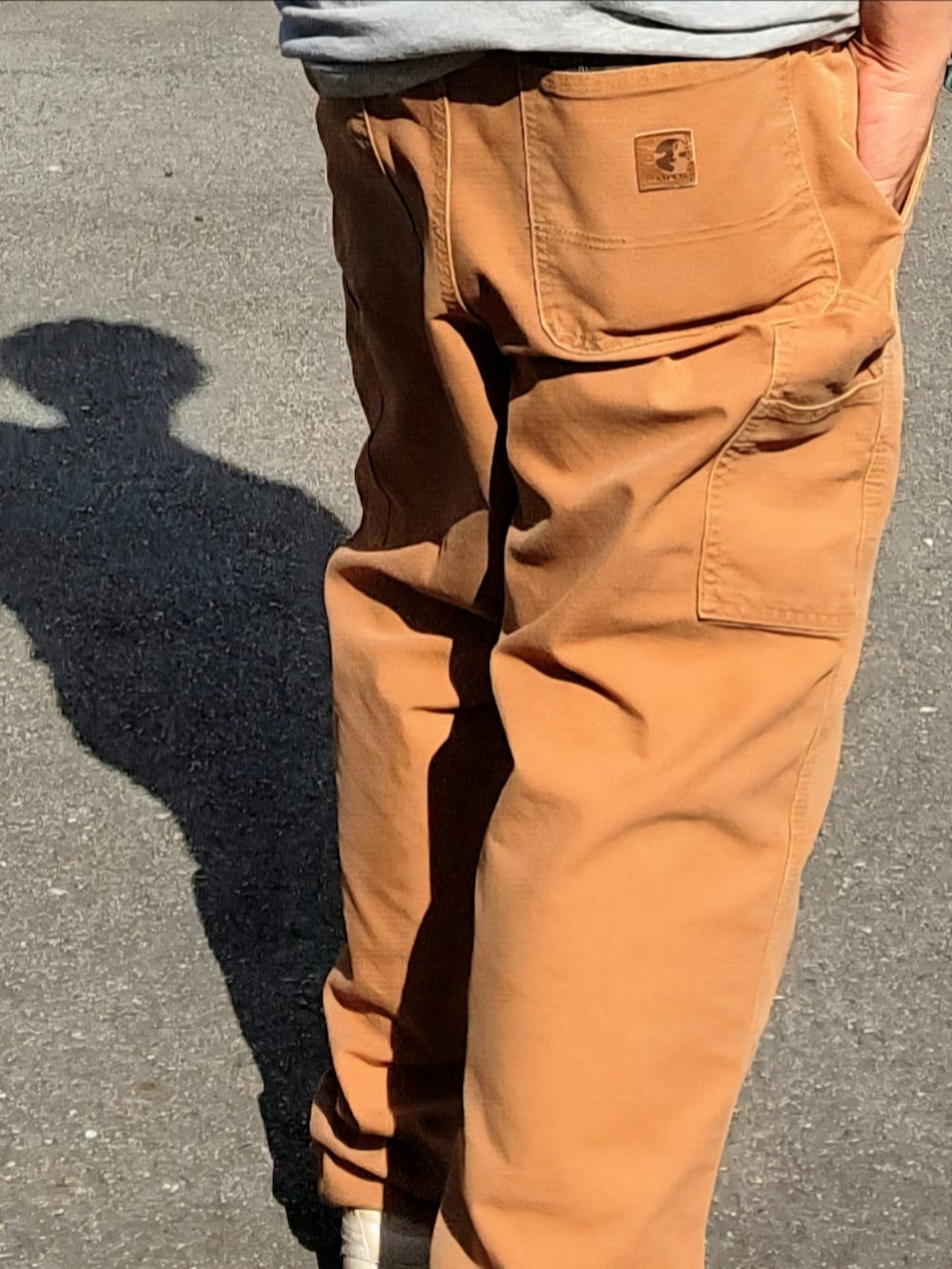 ブラック系のスニーカー、ブラウン系のチノパンツ、グレー系のTシャツ/カットソーを着用したメンズの春コーディネートの2枚目の写真