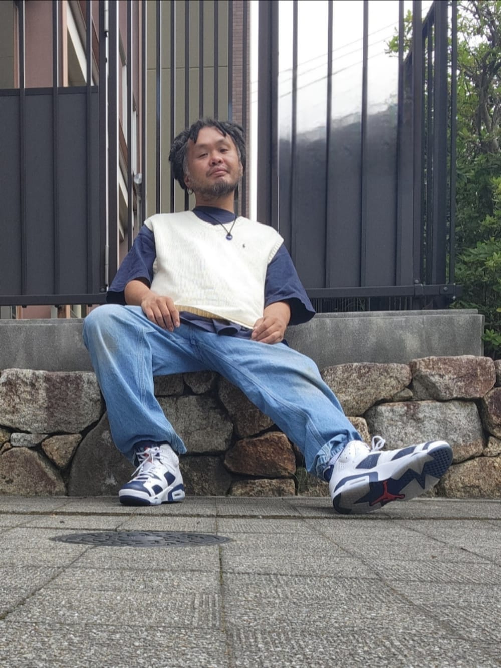 ホワイト系のスニーカー、ブルー系のデニムパンツ、ホワイト系のベストを着用したメンズの夏コーディネートの5枚目の写真