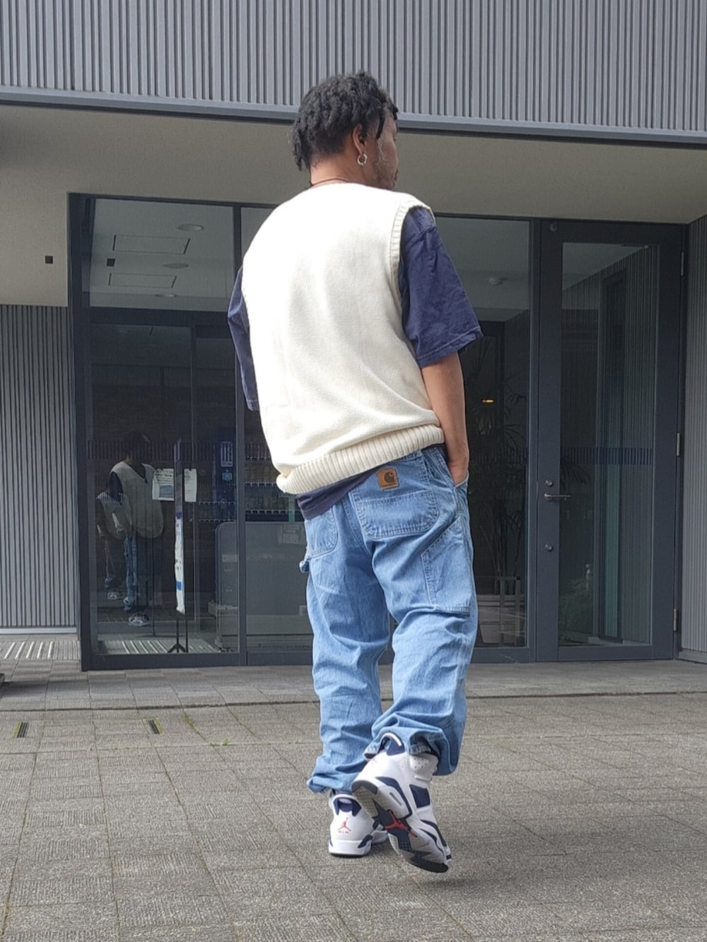ホワイト系のスニーカー、ブルー系のデニムパンツ、ホワイト系のベストを着用したメンズの夏コーディネートの4枚目の写真