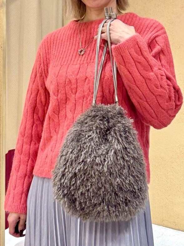 レッド系のニット/セーター、グレー系のスカート、ブラウン系のショルダーバッグを着用したレディースの冬コーディネートの4枚目の写真