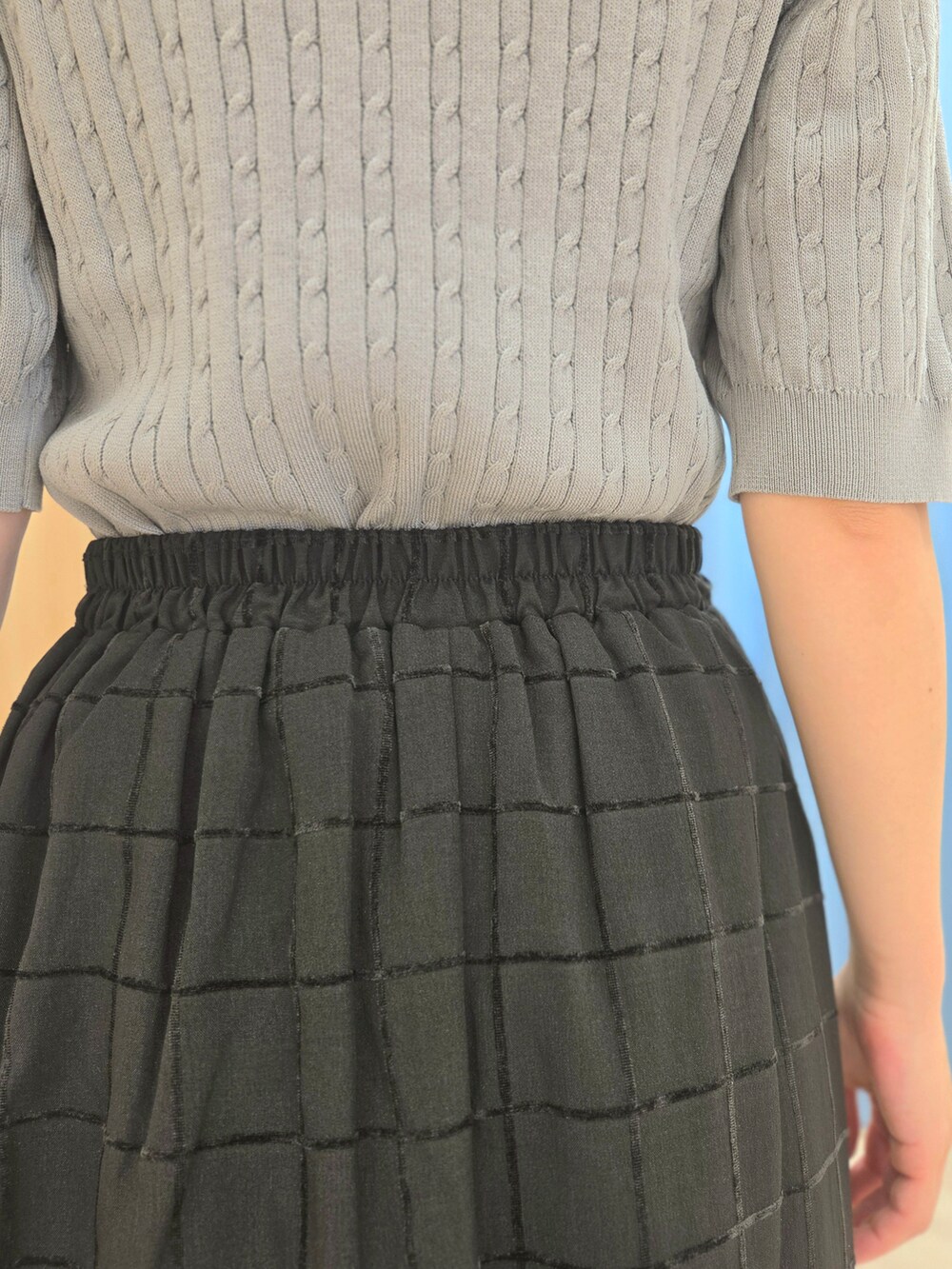 グレー系のニット/セーター、ブラック系のスカート、ブラック系のブーツを着用したレディースの秋コーディネートの8枚目の写真