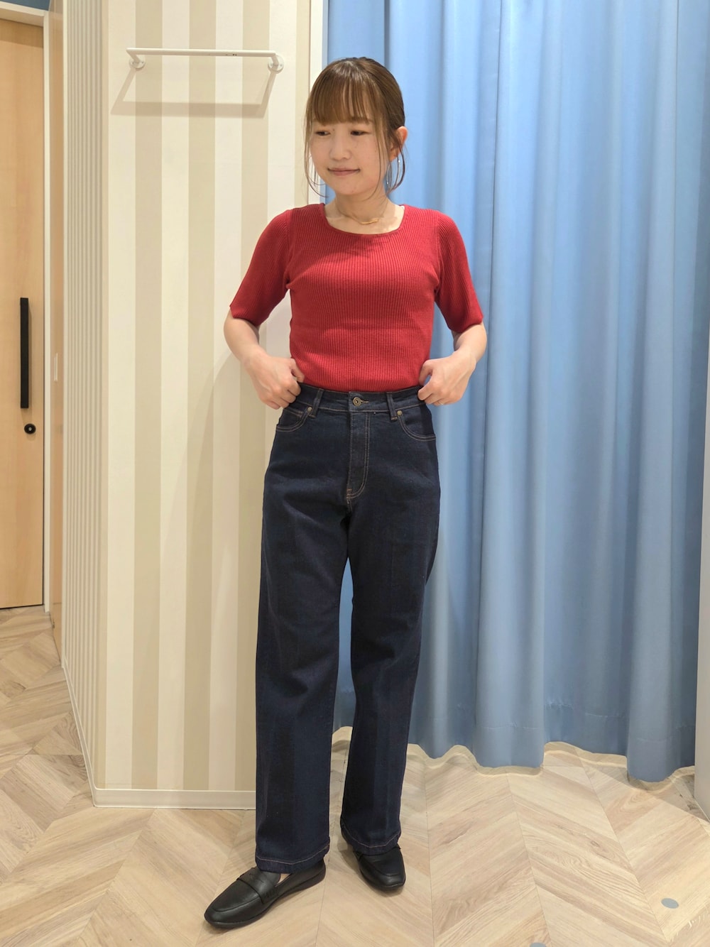 レッド系のニット/セーター、ホワイト系のTシャツ/カットソー、ブルー系のデニムパンツを着用したレディースの秋コーディネートの7枚目の写真