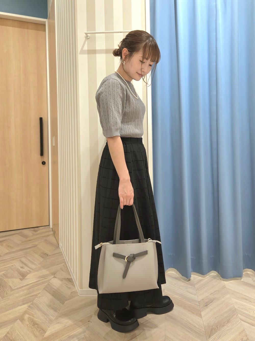 グレー系のニット/セーター、ブラック系のスカート、ブラック系のブーツを着用したレディースの秋コーディネートの2枚目の写真