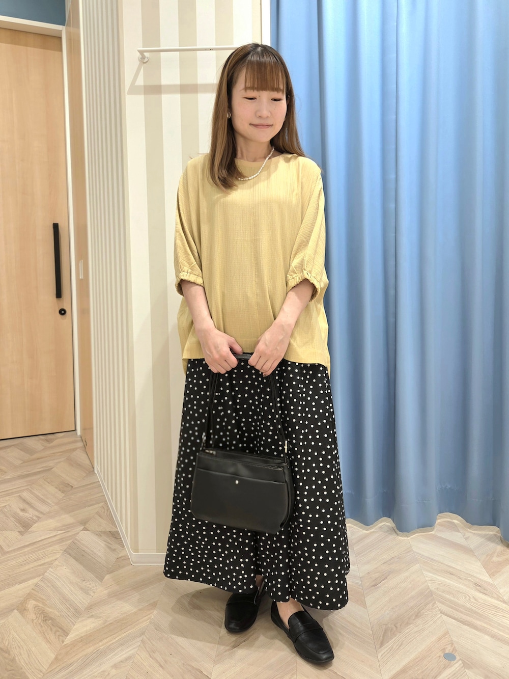 イエロー系のシャツ/ブラウス、ブラック系のスカート、ブラック系のパンプスを着用したレディースの秋コーディネートの7枚目の写真