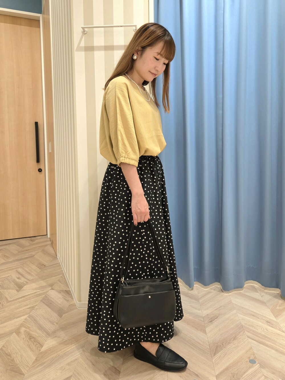 イエロー系のシャツ/ブラウス、ブラック系のスカート、ブラック系のパンプスを着用したレディースの秋コーディネートの3枚目の写真