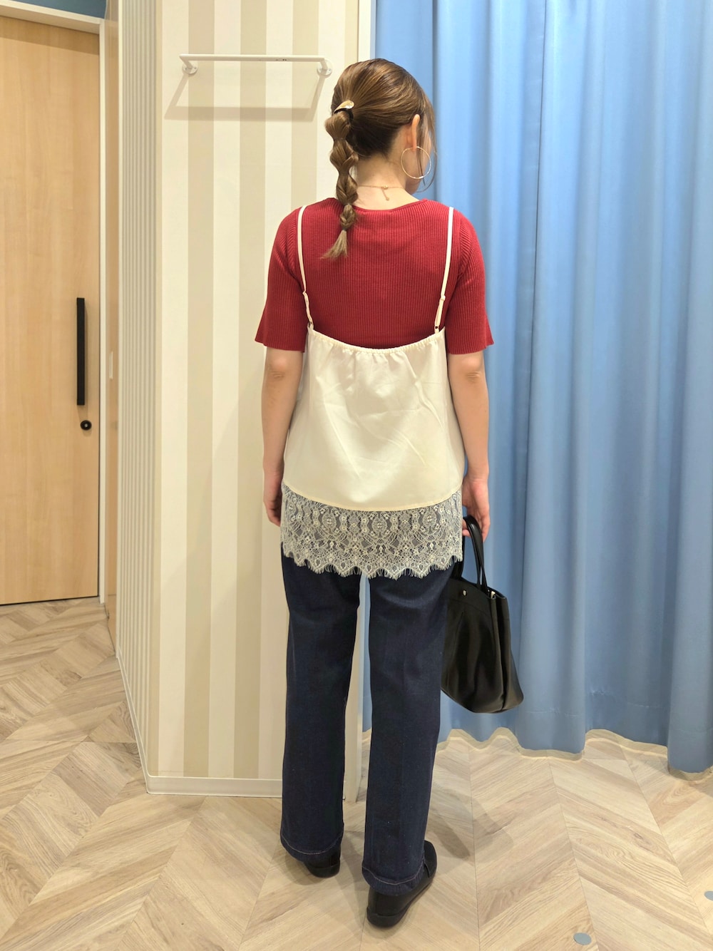 レッド系のニット/セーター、ホワイト系のTシャツ/カットソー、ブルー系のデニムパンツを着用したレディースの秋コーディネートの3枚目の写真