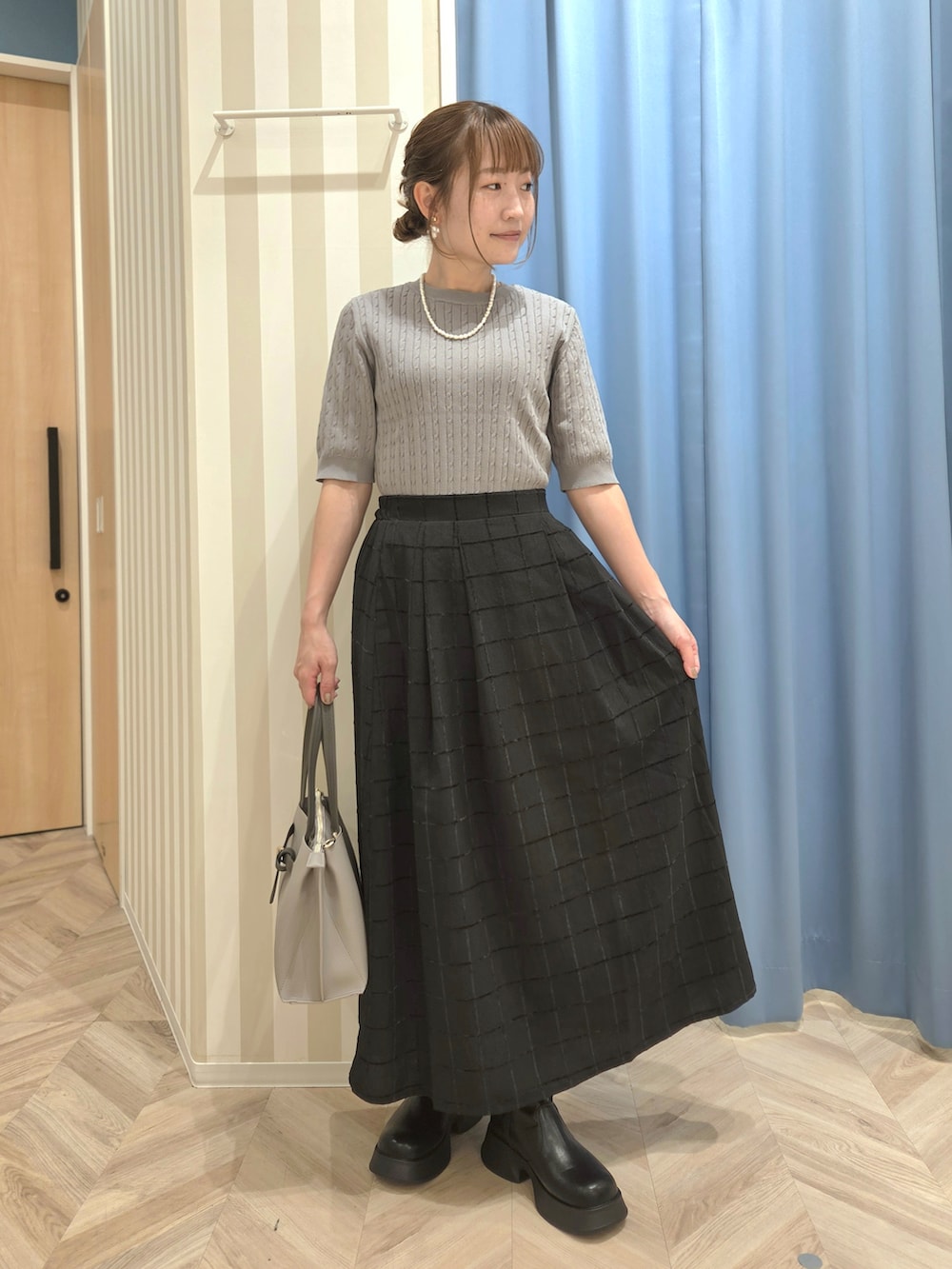 グレー系のニット/セーター、ブラック系のスカート、ブラック系のブーツを着用したレディースの秋コーディネートの5枚目の写真