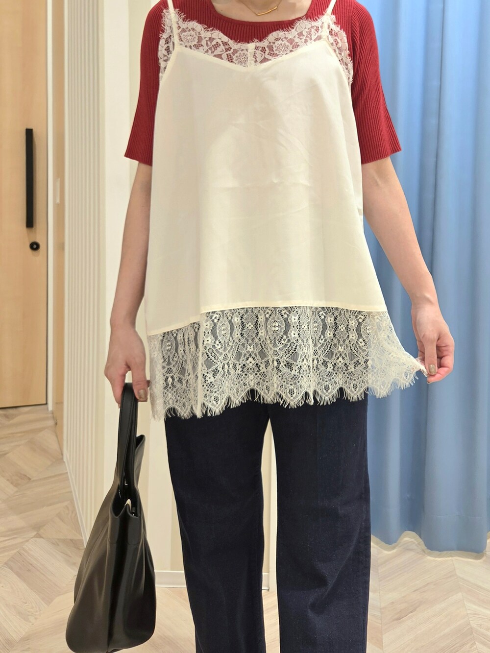 レッド系のニット/セーター、ホワイト系のTシャツ/カットソー、ブルー系のデニムパンツを着用したレディースの秋コーディネートの5枚目の写真
