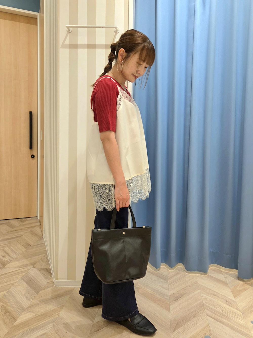 レッド系のニット/セーター、ホワイト系のTシャツ/カットソー、ブルー系のデニムパンツを着用したレディースの秋コーディネートの2枚目の写真