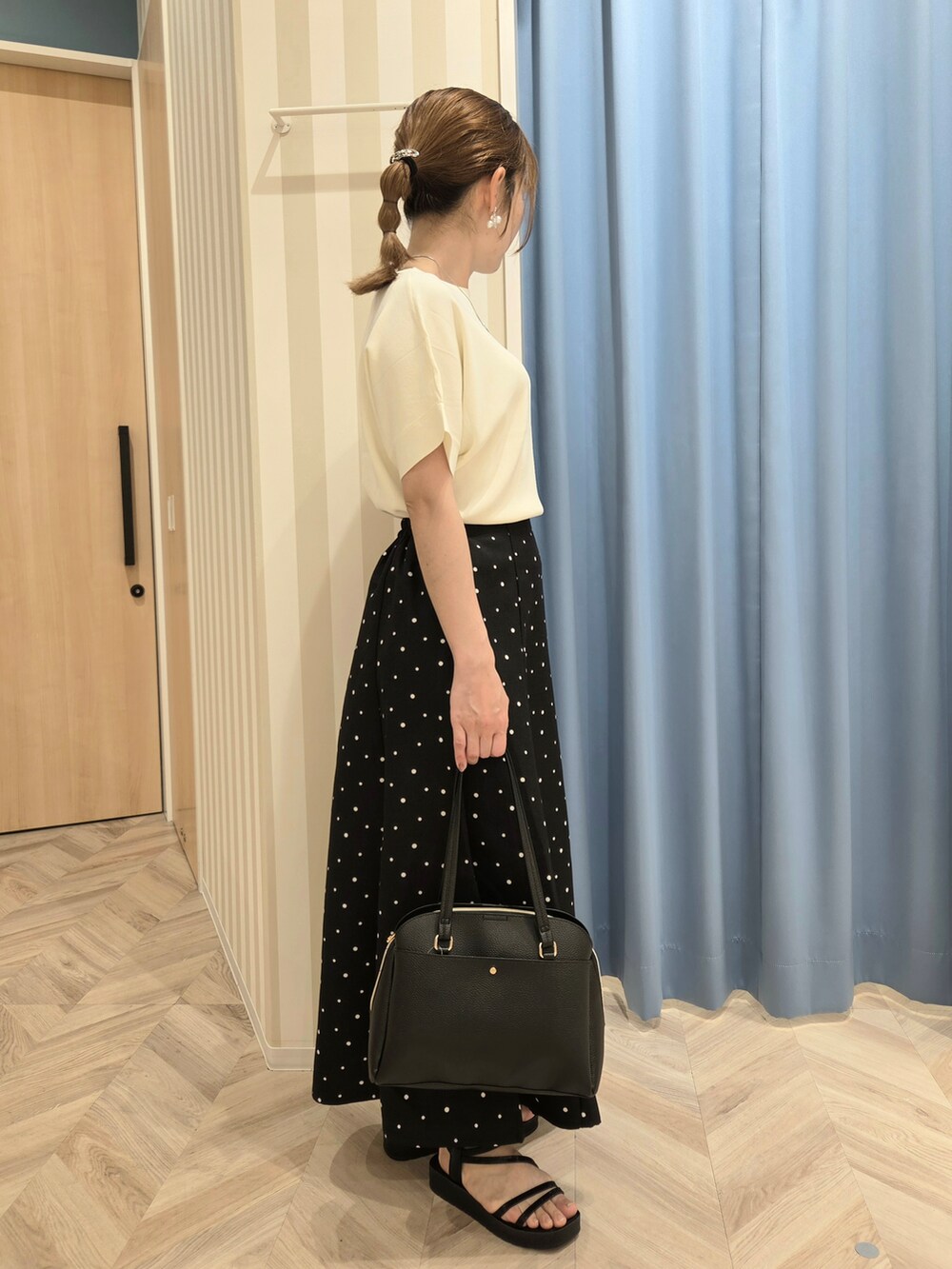 ホワイト系のニット/セーター、ブラック系のスカート、ブラック系のサンダルを着用したレディースの春コーディネートの2枚目の写真