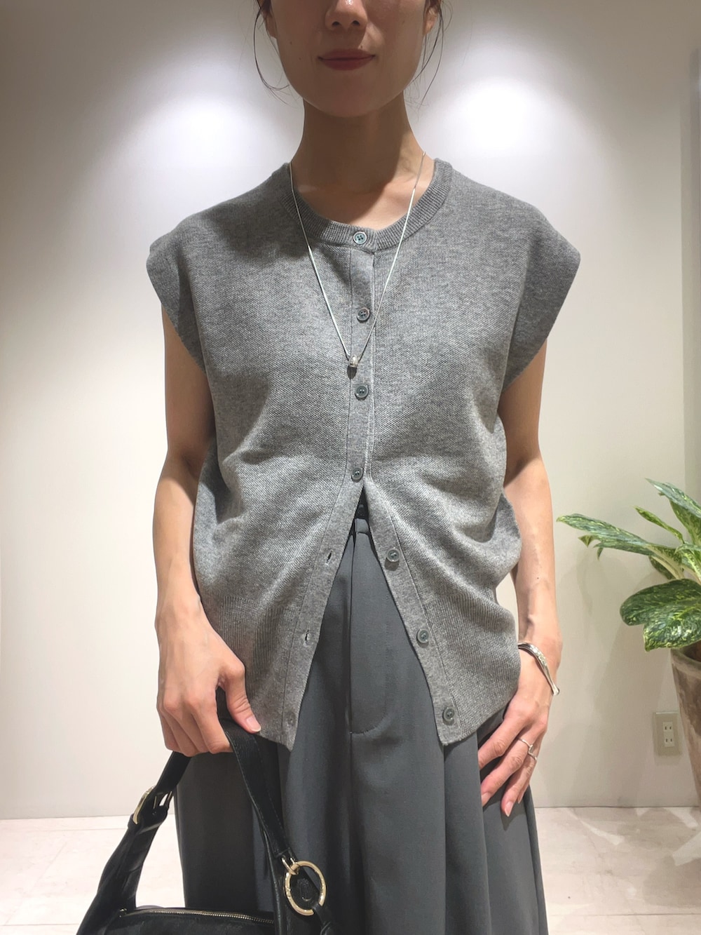 グレー系のその他パンツ、グレー系のニット/セーター、ブラック系のショルダーバッグを着用したレディースの夏コーディネートの2枚目の写真