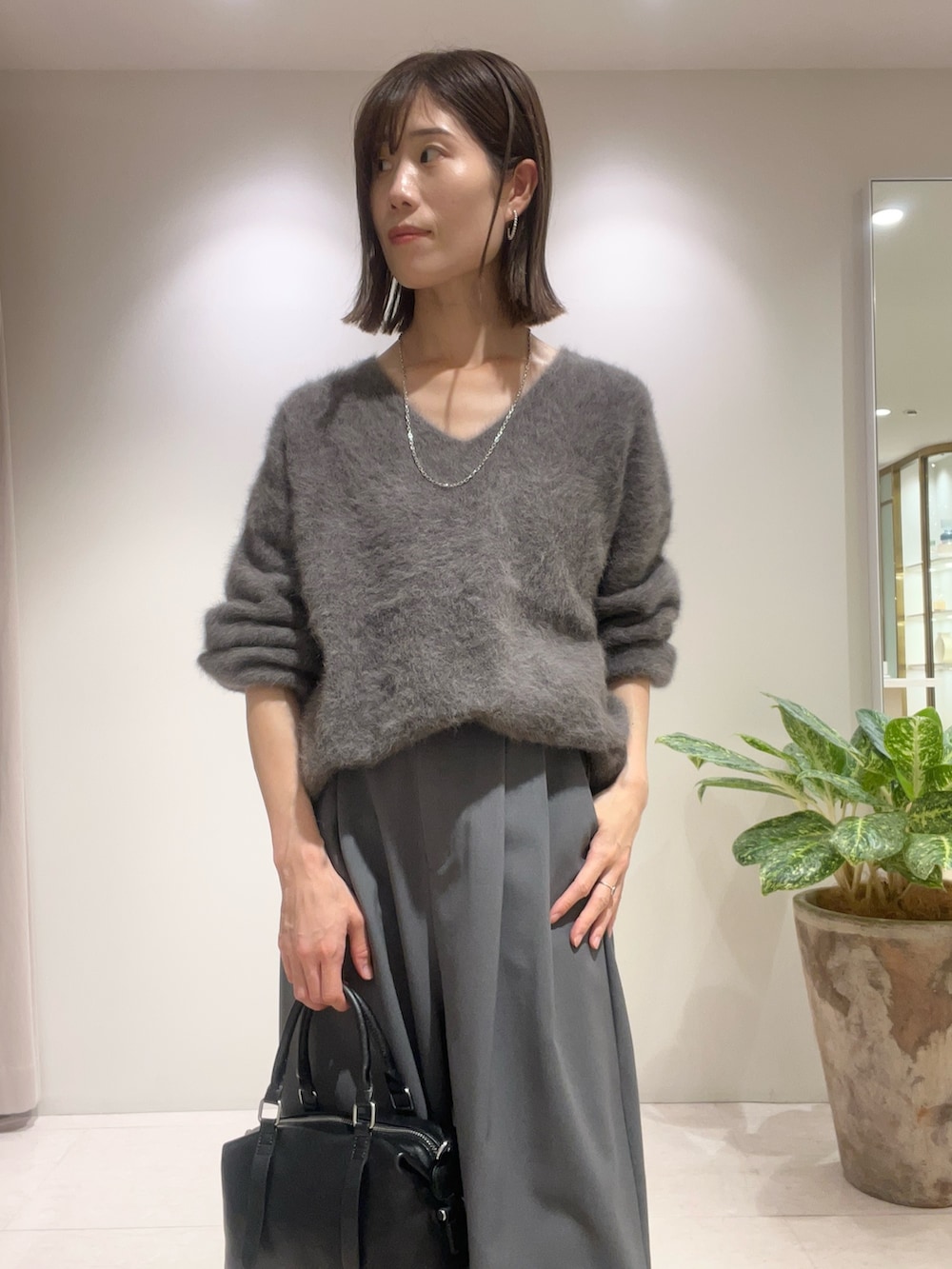 グレー系のその他パンツ、ブラック系のボストンバッグ、グレー系のニット/セーターを着用したレディースの秋コーディネートの2枚目の写真