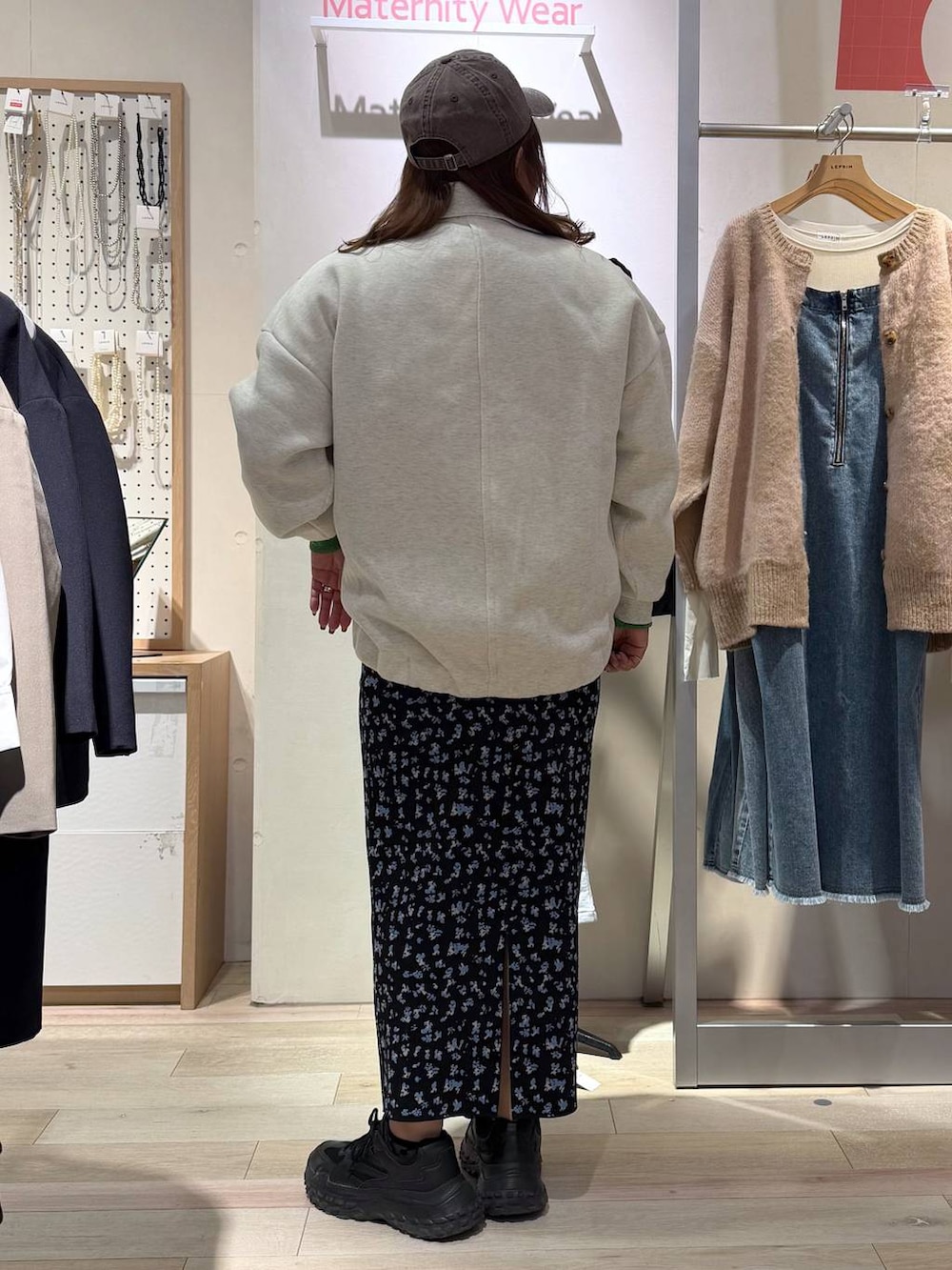 ブラック系のスカート、ホワイト系のカーディガン/ボレロ、ブラウン系のキャップを着用したレディースの冬コーディネートの3枚目の写真