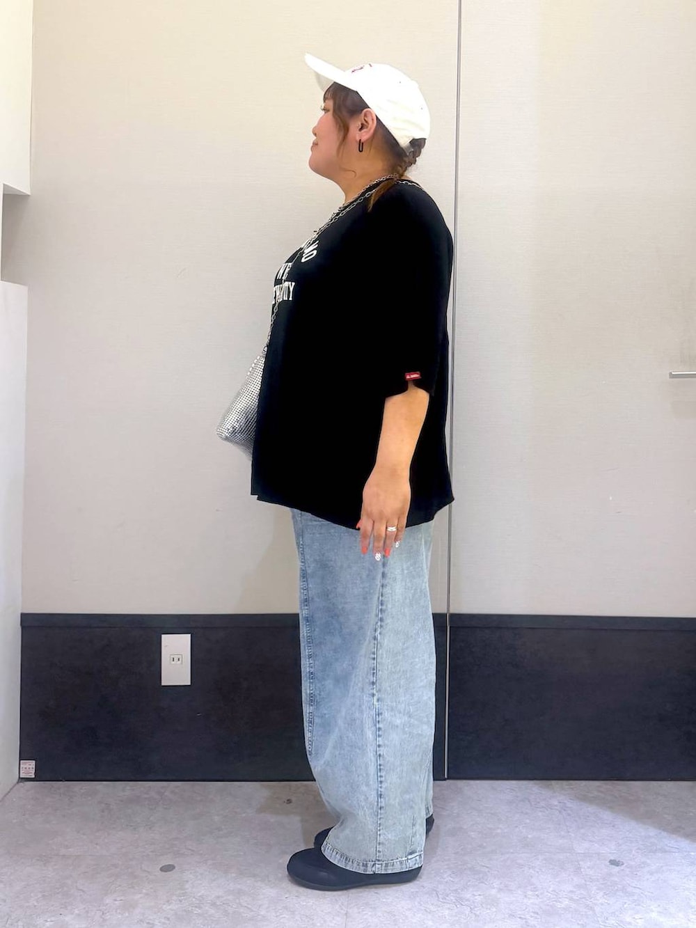 ブラック系のパンプス、シルバー系のショルダーバッグ、ブルー系のデニムパンツを着用したレディースの春コーディネートの2枚目の写真