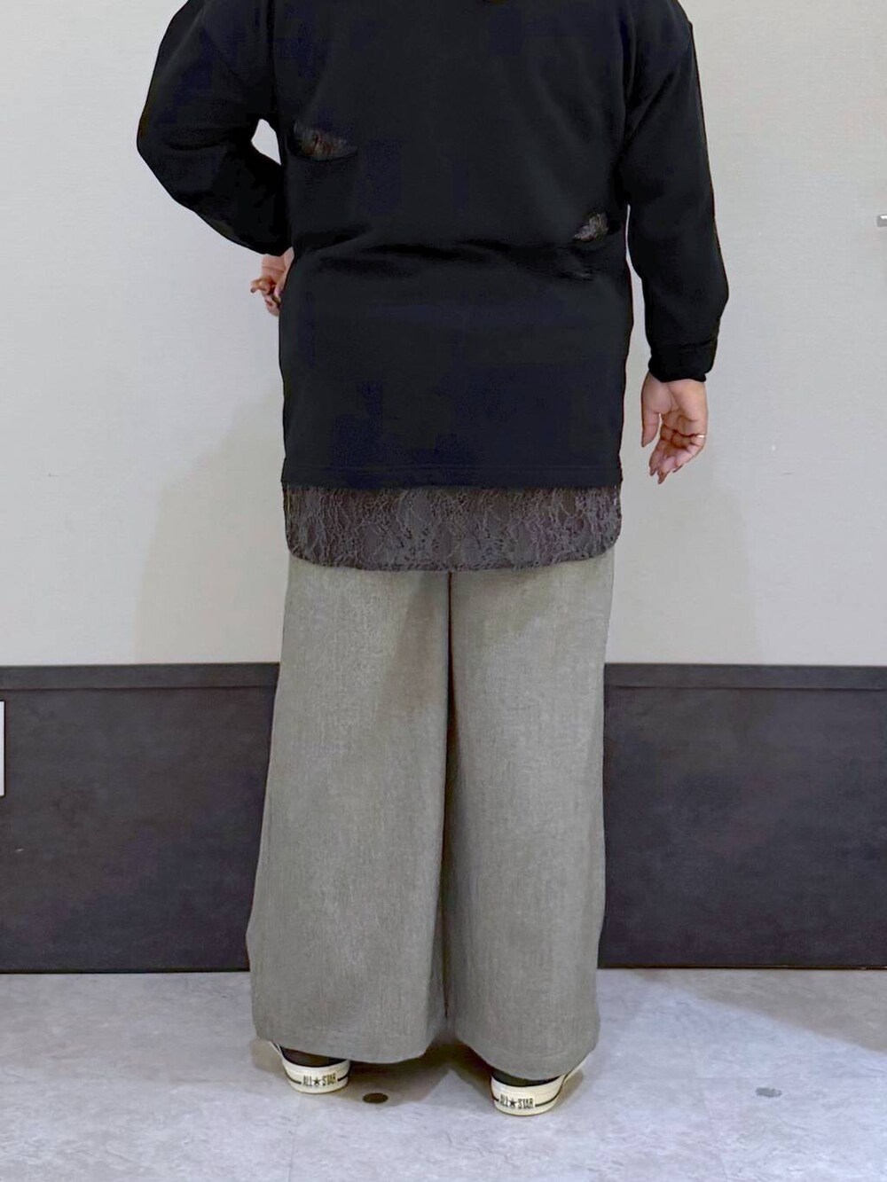 ブラック系のチュニック、ブラウン系のスニーカー、グレー系のスラックスを着用したレディースの秋コーディネートの3枚目の写真