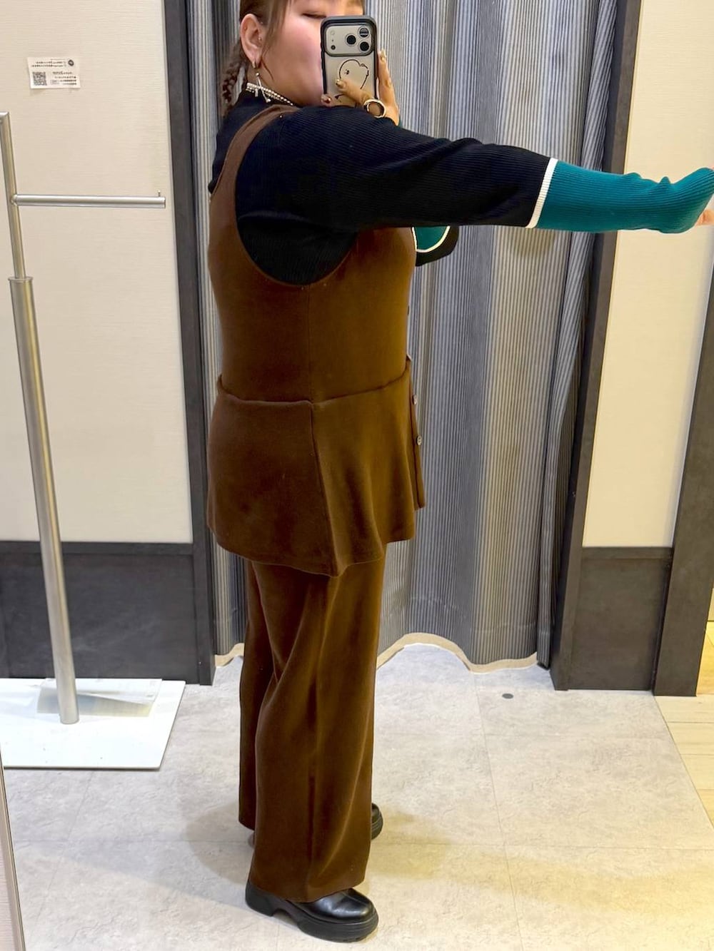 ブラック系のニット/セーター、ブラック系のブーツ、イエロー系のつなぎ/オールインワンを着用したレディースの冬コーディネートの2枚目の写真