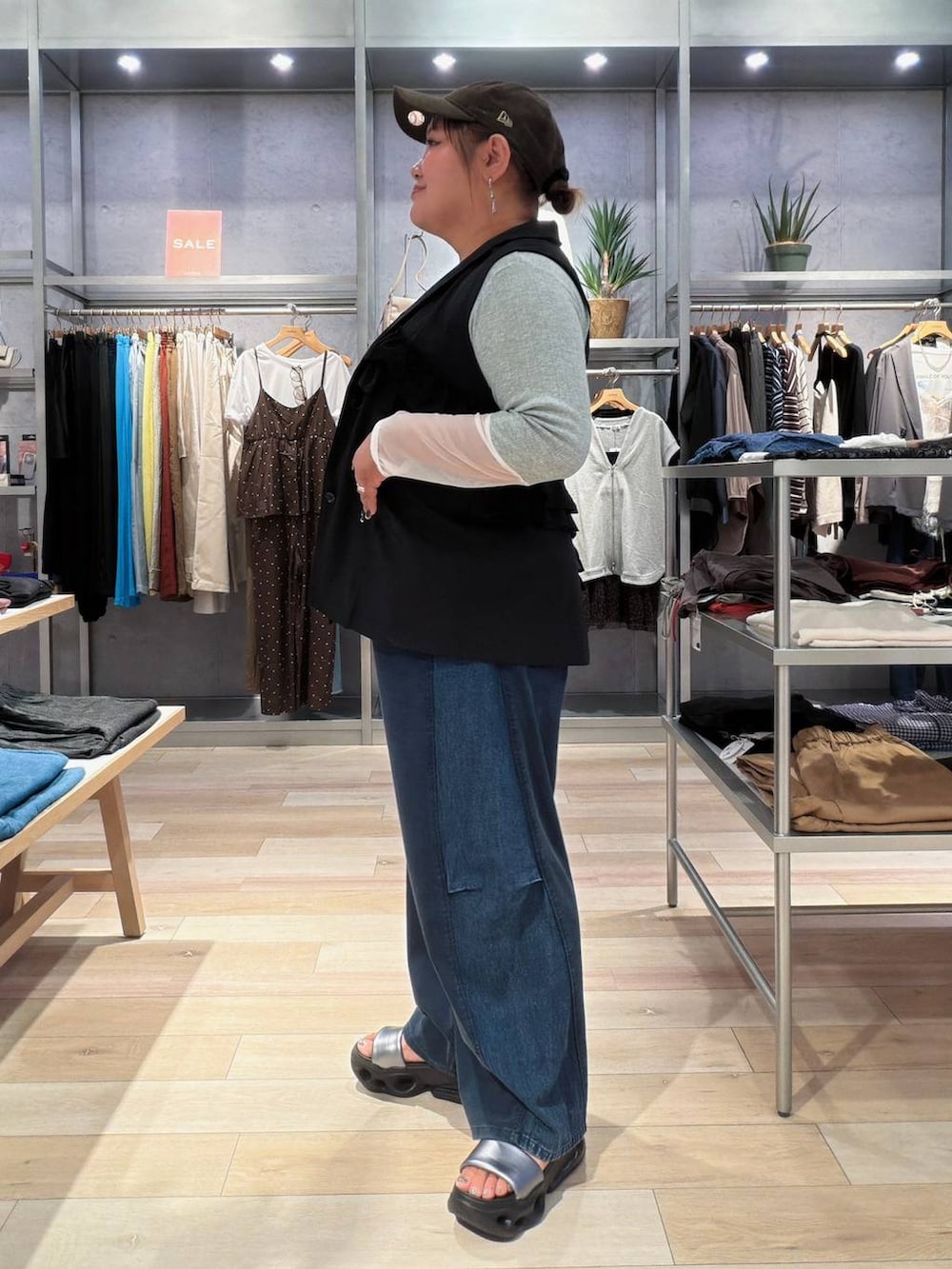 ブルー系のデニムパンツ、ブラック系のベスト、グレー系のTシャツ/カットソーを着用したレディースの秋コーディネートの2枚目の写真