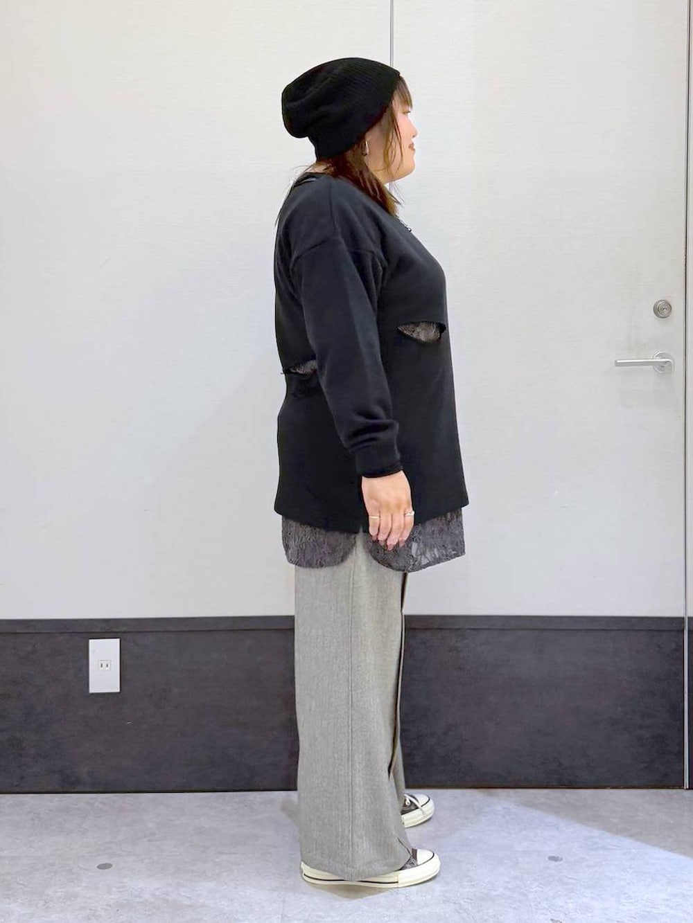 ブラック系のチュニック、ブラウン系のスニーカー、グレー系のスラックスを着用したレディースの秋コーディネートの2枚目の写真