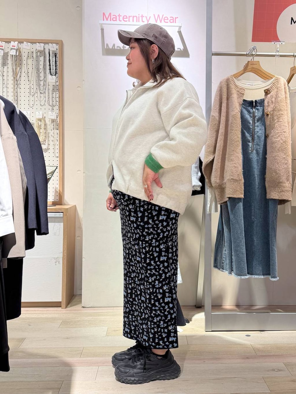 ブラック系のスカート、ホワイト系のカーディガン/ボレロ、ブラウン系のキャップを着用したレディースの冬コーディネートの2枚目の写真