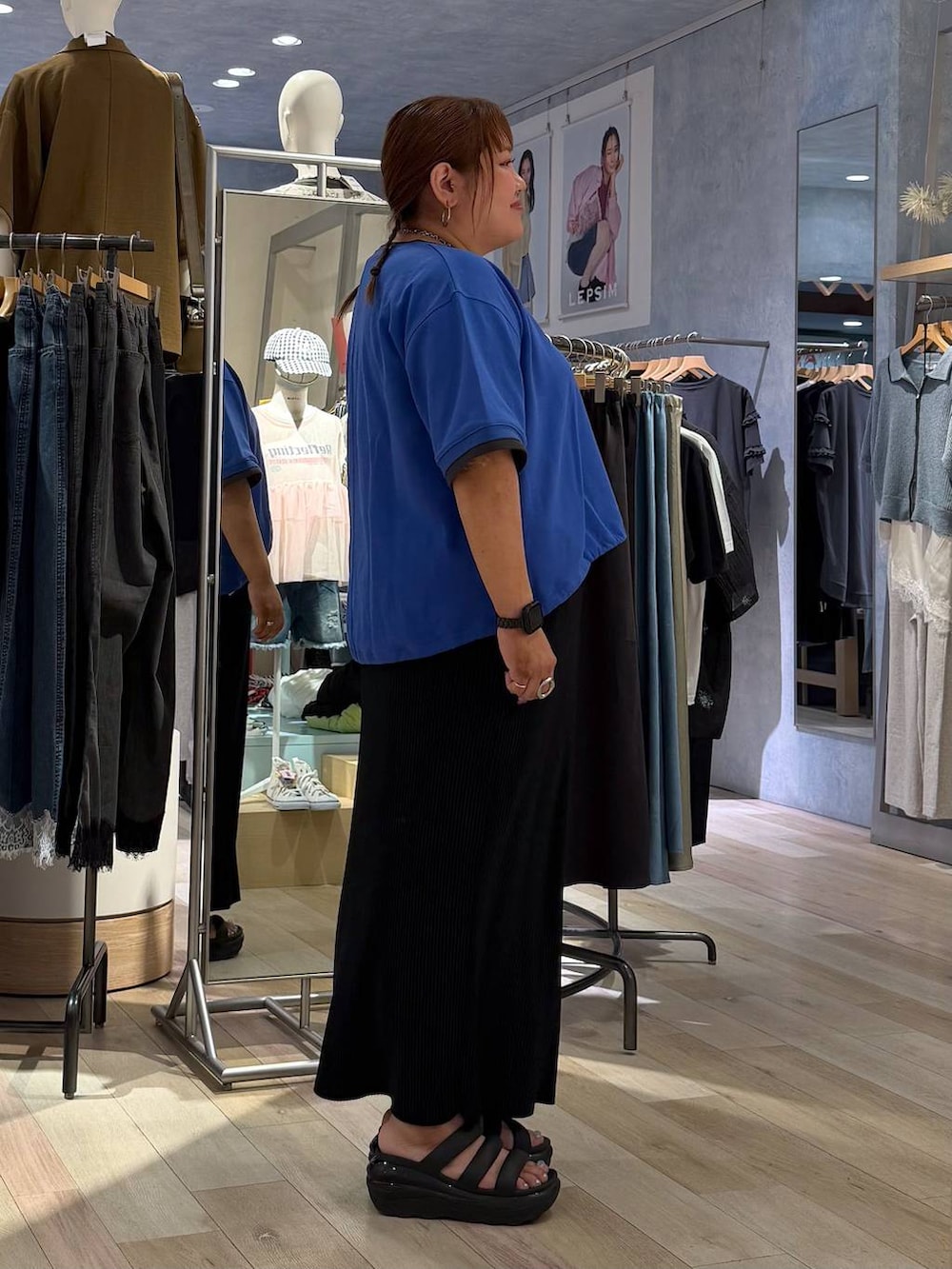 ブラック系のスカート、ブルー系のTシャツ/カットソー、シルバー系のネックレスを着用したレディースの春コーディネートの2枚目の写真