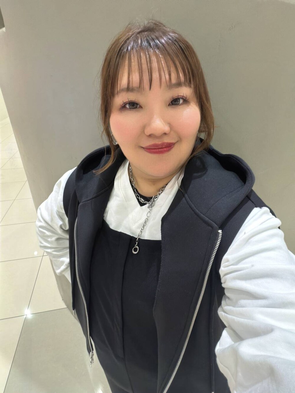 ブラック系のベスト、ホワイト系のTシャツ/カットソー、ブラック系のマタニティウェア/グッズを着用したレディースの冬コーディネートの4枚目の写真