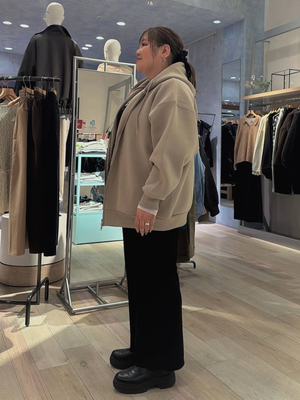 ホワイト系のTシャツ/カットソー、ベージュ系のパーカー、ブラック系のブーツを着用したレディースの冬コーディネートの2枚目の写真