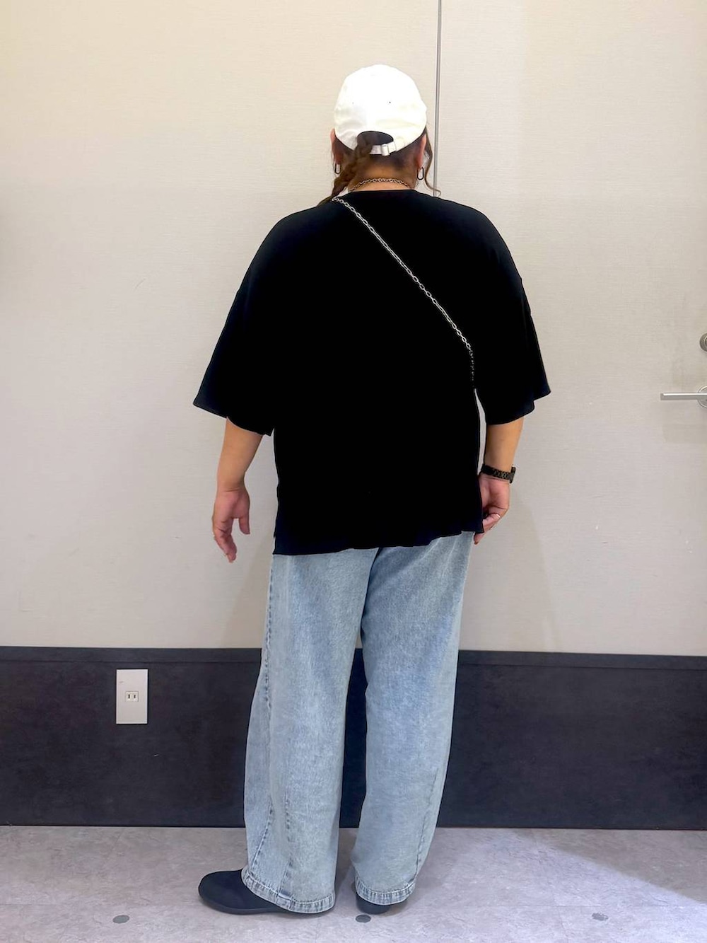 ブラック系のパンプス、シルバー系のショルダーバッグ、ブルー系のデニムパンツを着用したレディースの春コーディネートの4枚目の写真