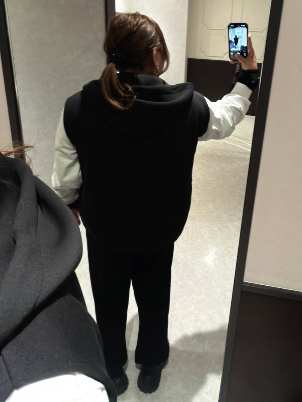 ブラック系のベスト、ホワイト系のTシャツ/カットソー、ブラック系のマタニティウェア/グッズを着用したレディースの冬コーディネートの3枚目の写真