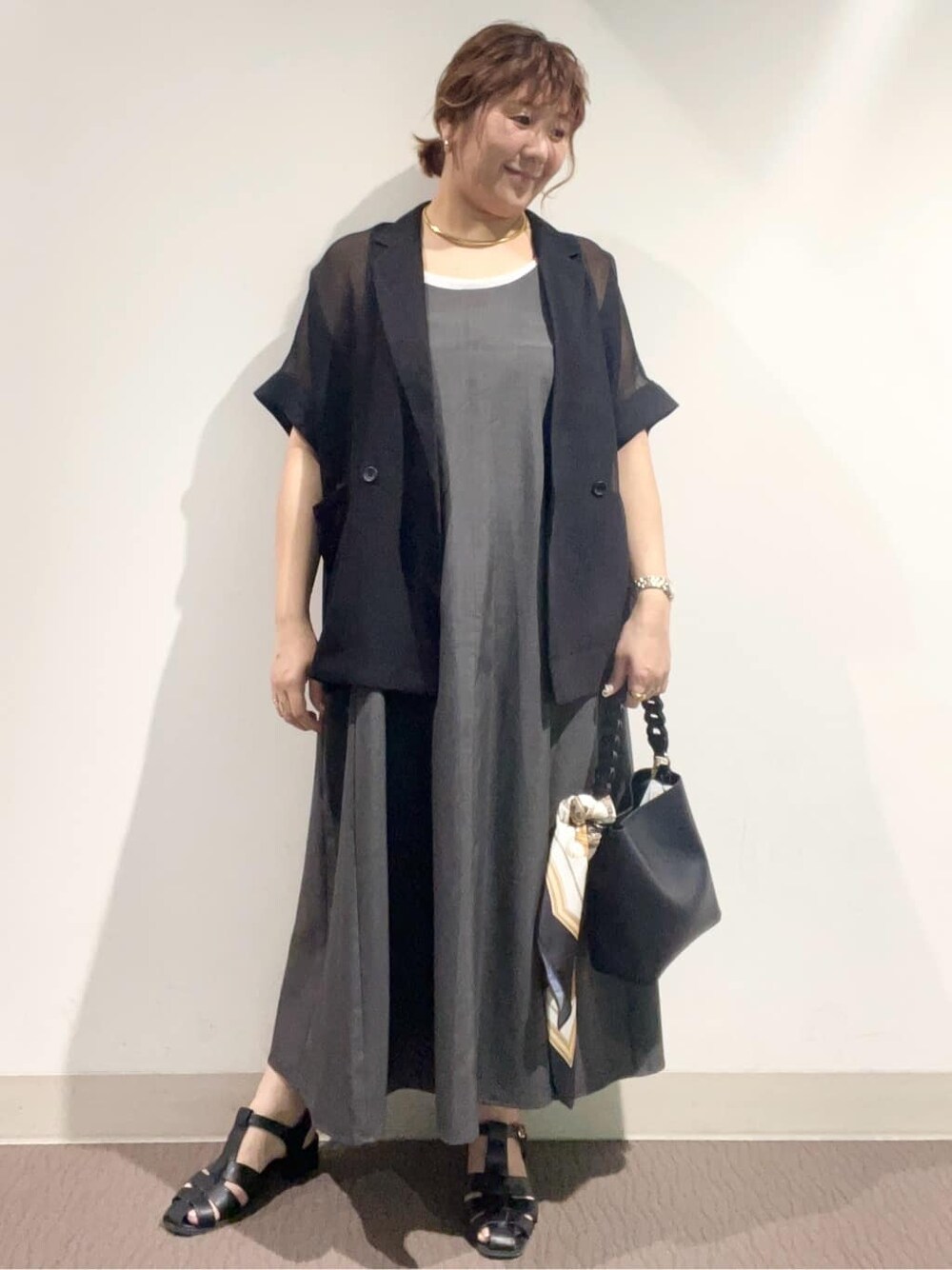 グレー系のワンピース、ブラック系のショルダーバッグ、ブラック系のサンダルを着用したレディースの夏コーディネートの3枚目の写真