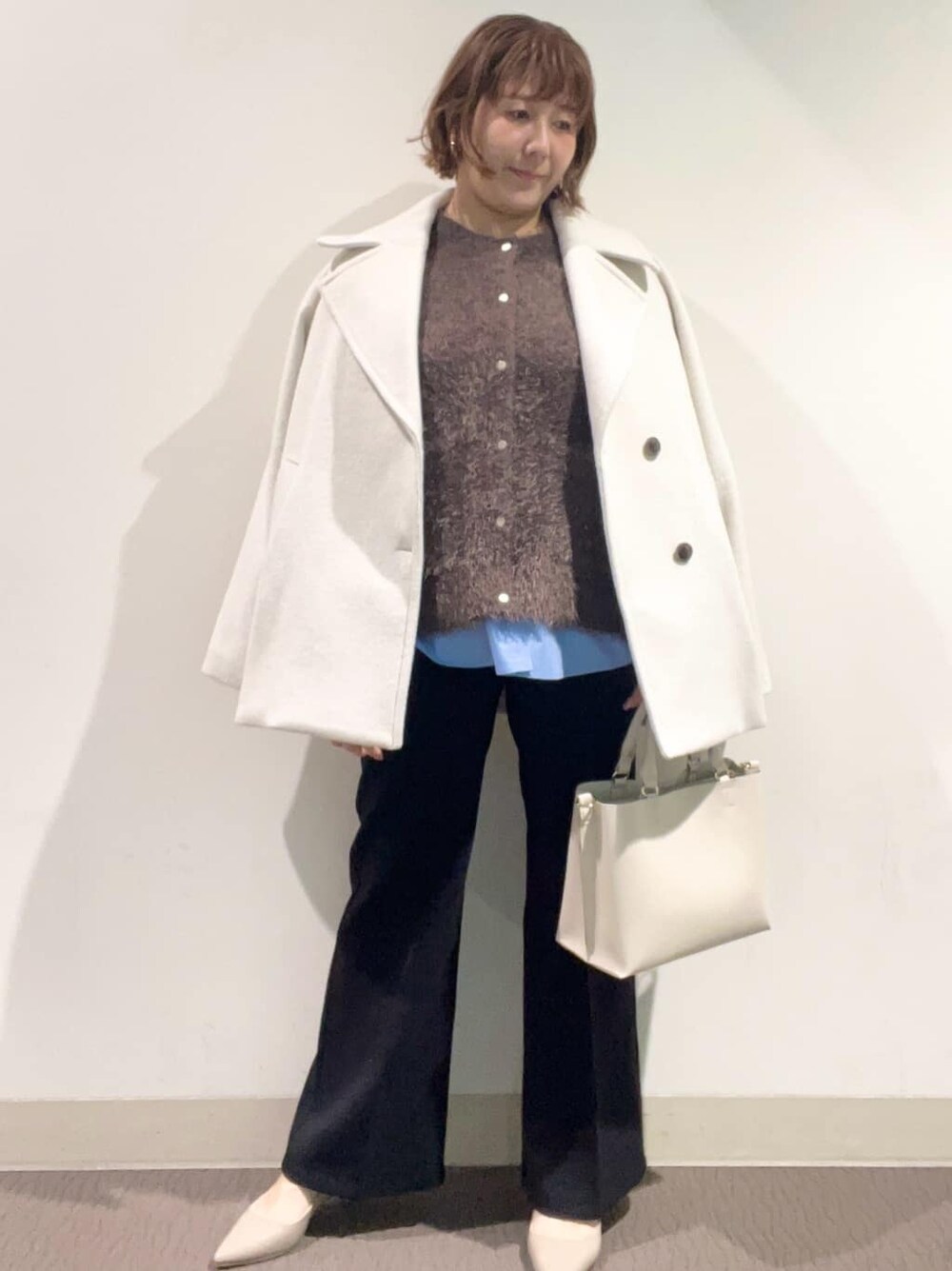 ホワイト系のピーコート、ブラウン系のカーディガン/ボレロ、ブルー系のTシャツ/カットソーを着用したレディースの冬コーディネートの2枚目の写真