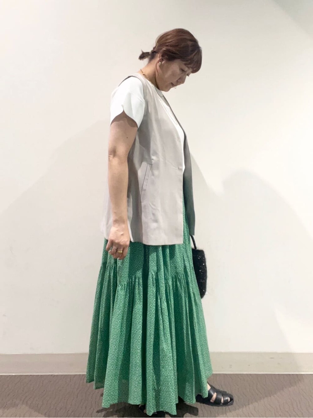 ホワイト系のニット/セーター、グレー系のベスト、ブラック系のトートバッグを着用したレディースの夏コーディネートの2枚目の写真