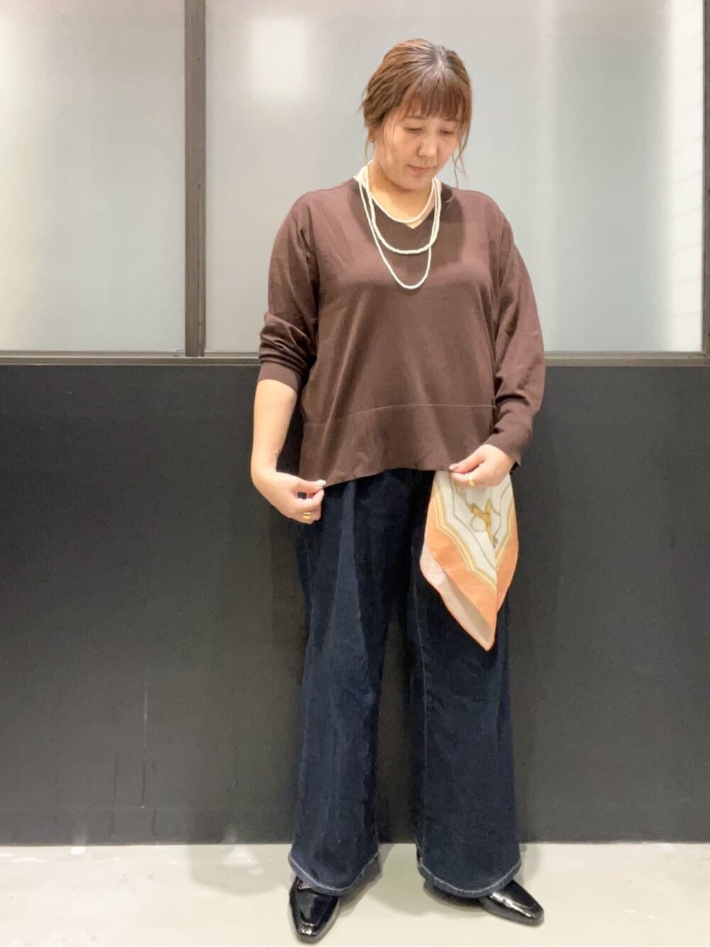 ブラウン系のニット/セーター、ブルー系のデニムパンツ、ブラック系のパンプスを着用したレディースの秋コーディネートの4枚目の写真