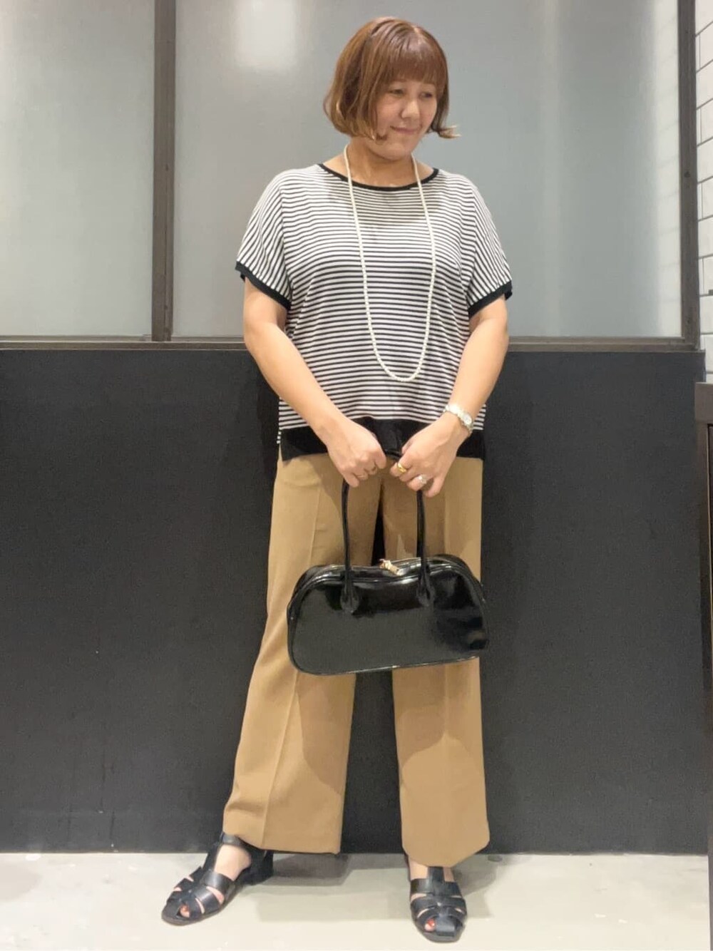 ブラック系のニット/セーター、イエロー系のその他パンツ、ブラック系のボストンバッグを着用したレディースの夏コーディネートの2枚目の写真