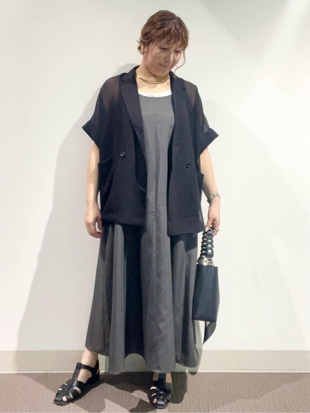 グレー系のワンピース、ブラック系のショルダーバッグ、ブラック系のサンダルを着用したレディースの夏コーディネートの5枚目の写真