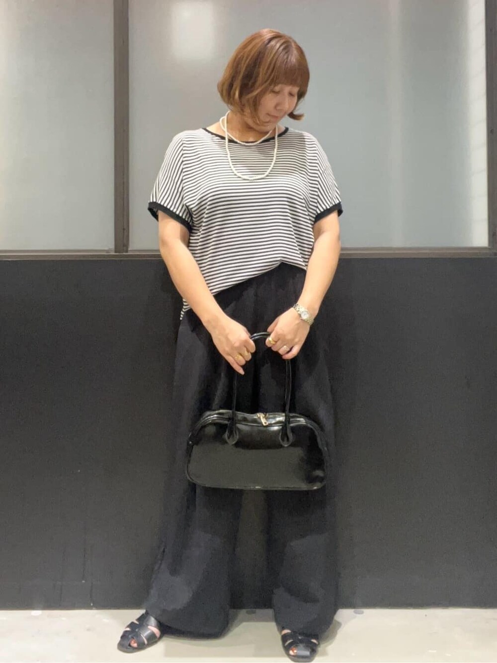 ブラック系のニット/セーター、ブラック系のその他パンツ、ブラック系のボストンバッグを着用したレディースの夏コーディネートの2枚目の写真