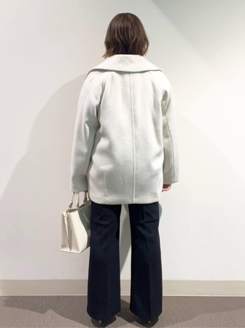 ホワイト系のピーコート、ブラウン系のカーディガン/ボレロ、ブルー系のTシャツ/カットソーを着用したレディースの冬コーディネートの4枚目の写真