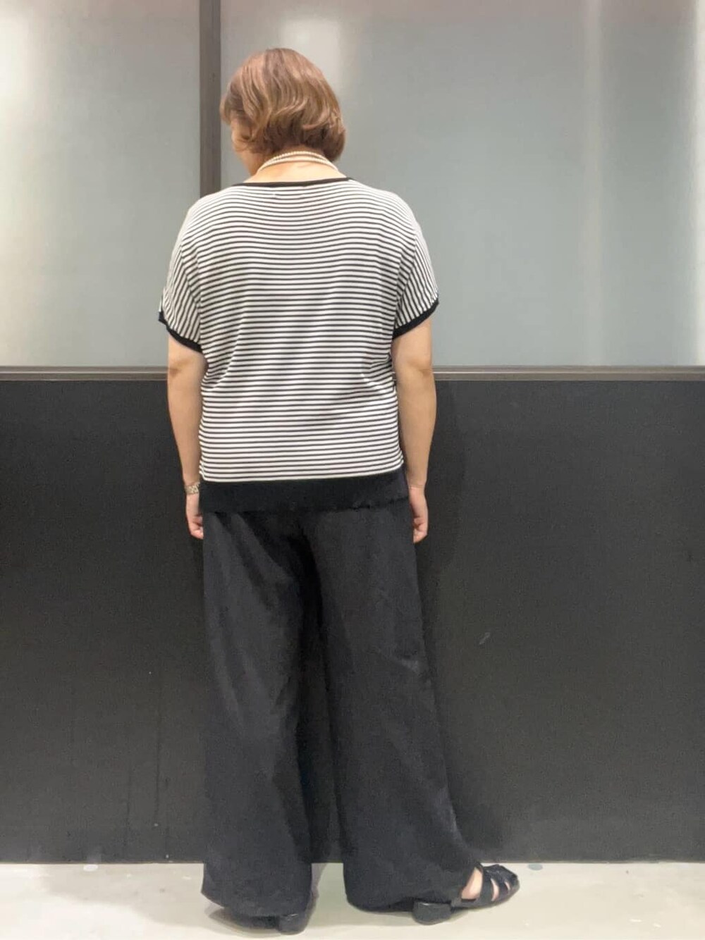 ブラック系のニット/セーター、ブラック系のその他パンツ、ブラック系のボストンバッグを着用したレディースの夏コーディネートの3枚目の写真