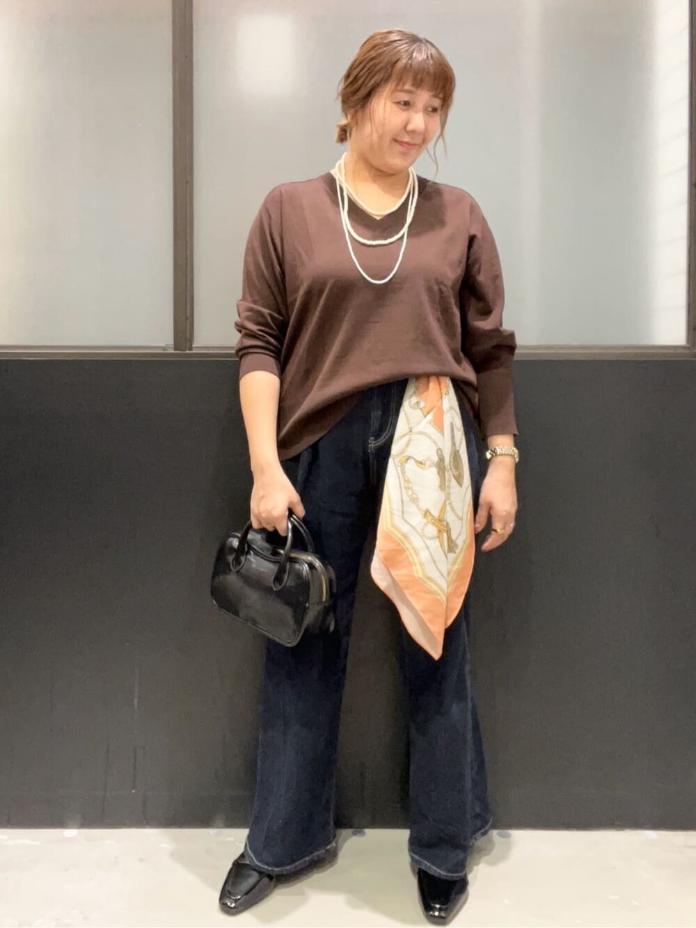 ブラウン系のニット/セーター、ブルー系のデニムパンツ、ブラック系のパンプスを着用したレディースの秋コーディネートの2枚目の写真