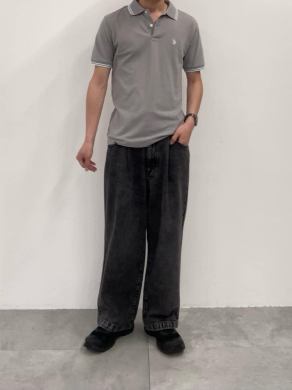 ブラック系のデニムパンツ、グレー系のポロシャツを着用したメンズの春コーディネートの2枚目の写真