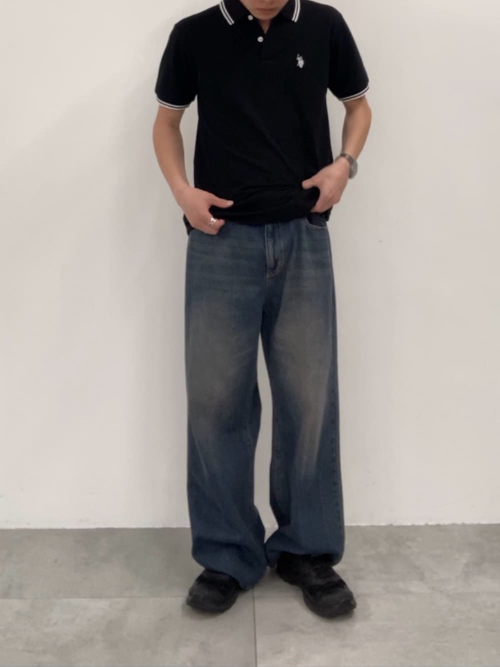 ブルー系のデニムパンツ、ブラック系のポロシャツを着用したメンズの春コーディネートの2枚目の写真