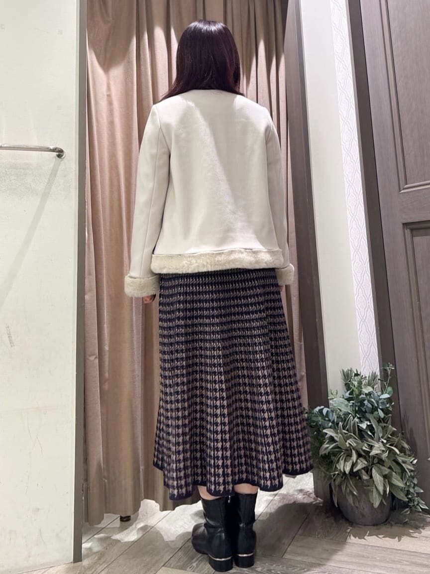 ベージュ系のノーカラーコート、ブルー系のニット/セーター、ブルー系のスカートを着用したレディースの冬コーディネートの3枚目の写真