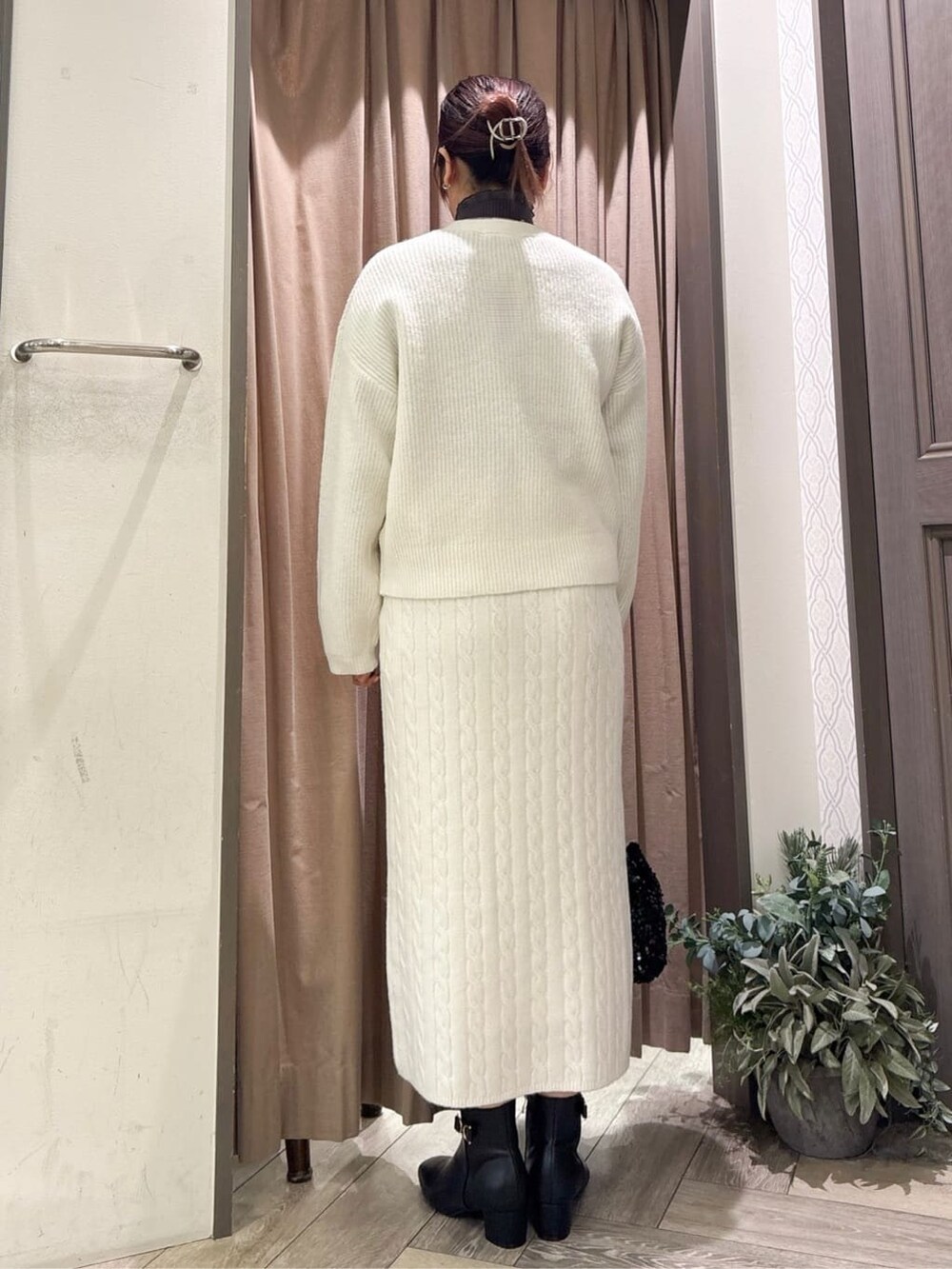 グレー系のニット/セーター、ホワイト系のカーディガン/ボレロ、ホワイト系のスカートを着用したレディースの秋コーディネートの3枚目の写真