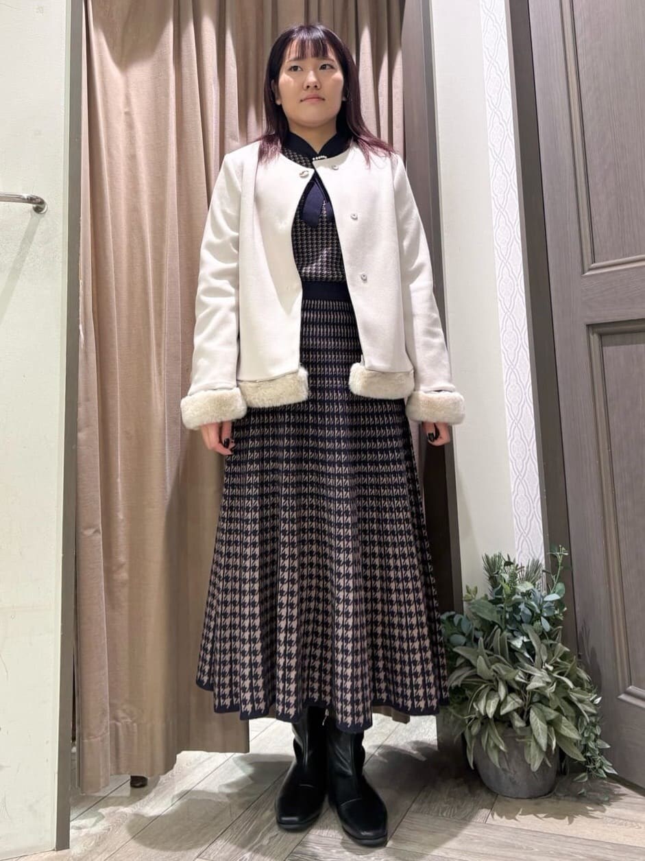 ベージュ系のノーカラーコート、ブルー系のニット/セーター、ブルー系のスカートを着用したレディースの冬コーディネートの4枚目の写真