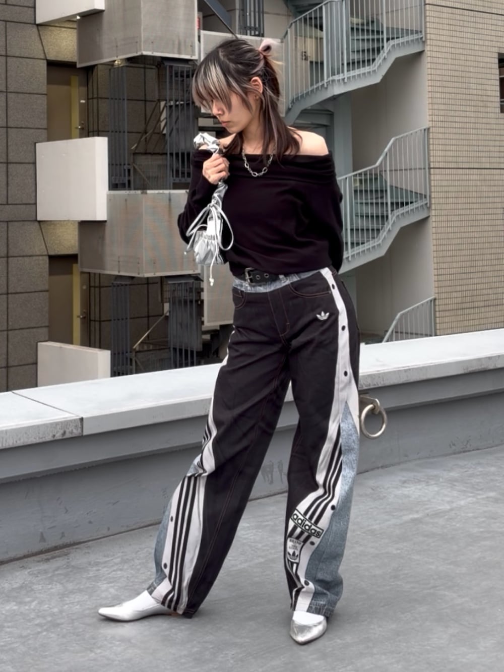 ブルー系のデニムパンツ、ブラック系のニット/セーター、シルバー系のハンドバッグを着用したレディースの冬コーディネートの4枚目の写真