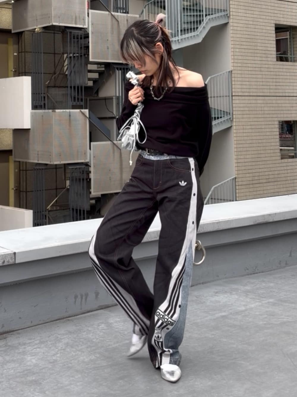 ブルー系のデニムパンツ、ブラック系のニット/セーター、シルバー系のハンドバッグを着用したレディースの冬コーディネートの3枚目の写真