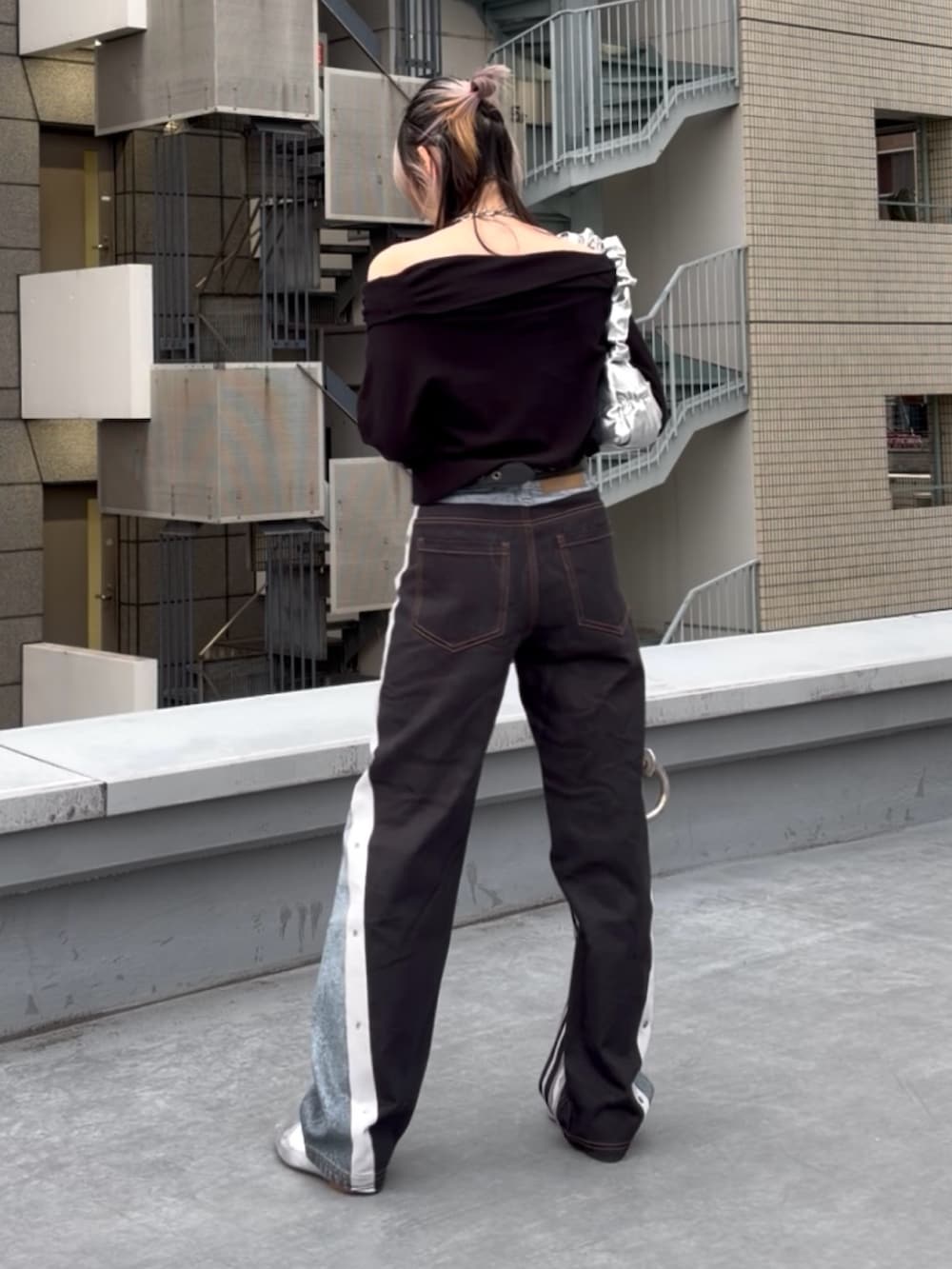 ブルー系のデニムパンツ、ブラック系のニット/セーター、シルバー系のハンドバッグを着用したレディースの冬コーディネートの2枚目の写真