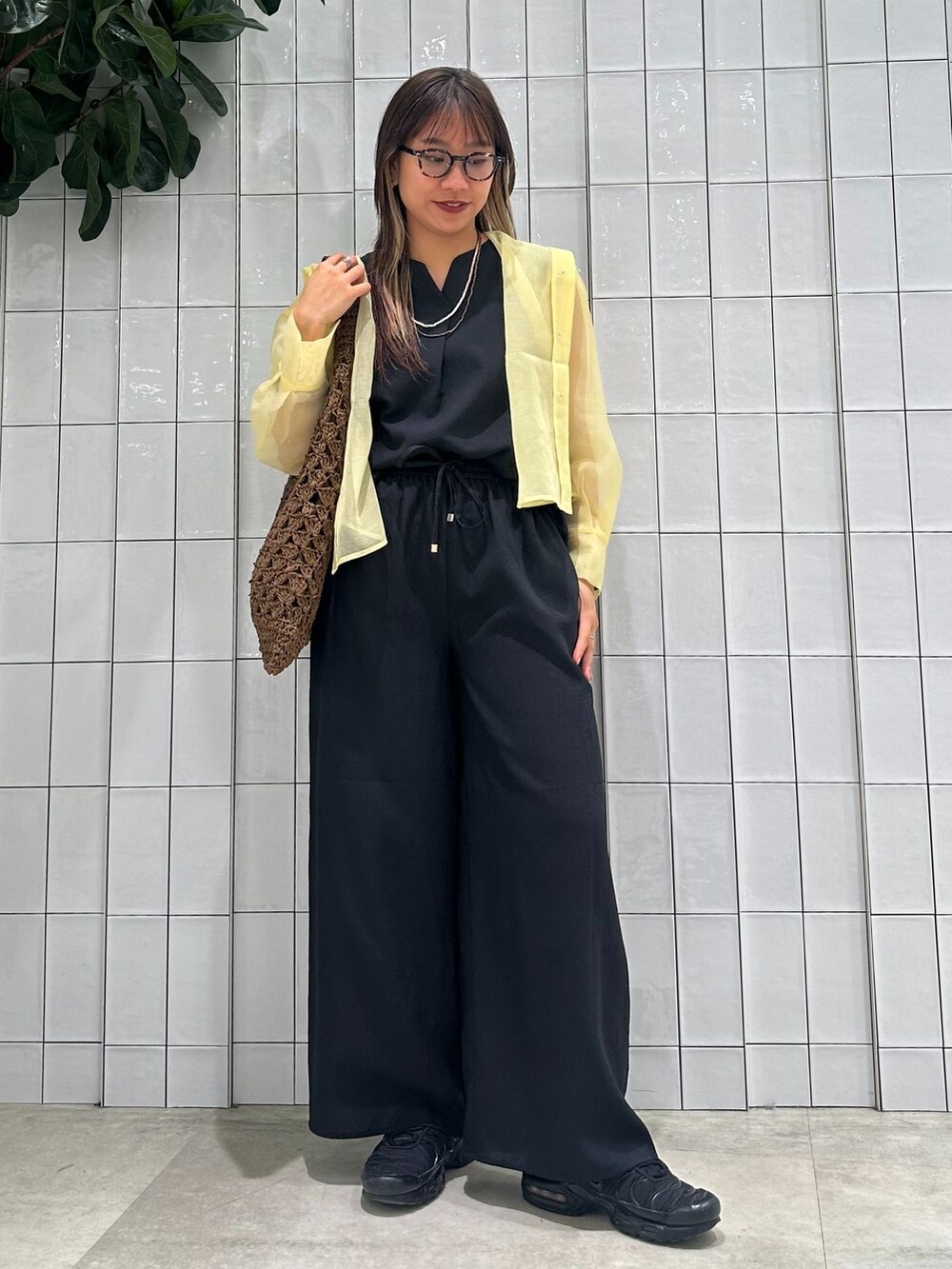 イエロー系のブルゾン、ブラック系のその他パンツ、ブラウン系のトートバッグを着用したレディースの春コーディネートの2枚目の写真