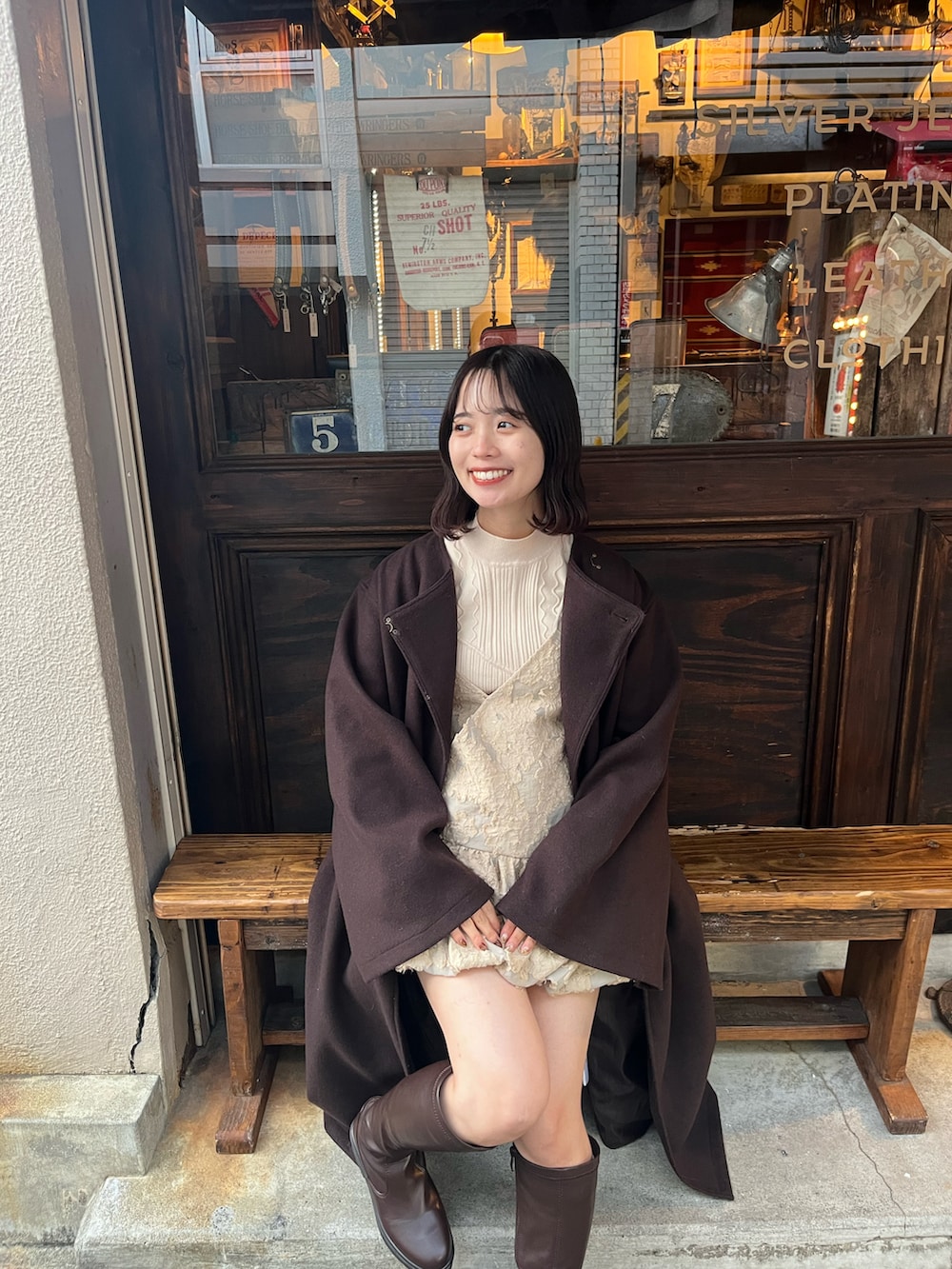 ブラウン系のブーツ、ブラウン系のノーカラーコート、ベージュ系のキャミソールを着用したレディースの冬コーディネートの2枚目の写真